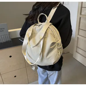 Detail view of cream nylon backpack with pleated texture and elastic side pockets