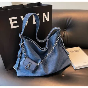 Detail of blue denim tote bag with silver chain decor and matching mini coin purse