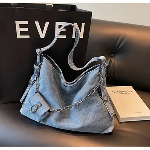 Detail of light blue denim hobo bag with silver chain and matching mini pouch accessory