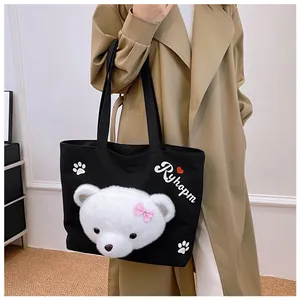 Detail of cute plush bear head and heart patterns on large black canvas tote bag