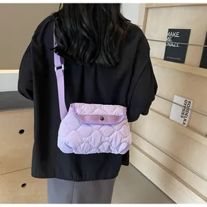 Side view of a purple quilted crossbody bag with wave stitching on a black jacket