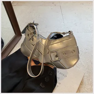 Detail view of silver crescent bag with adjustable buckles and metallic eyelet decor