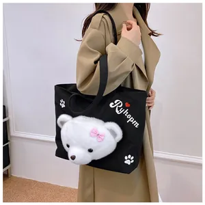Close-up of a black canvas tote with a 3D plush bear head and printed Ryhopm lettering