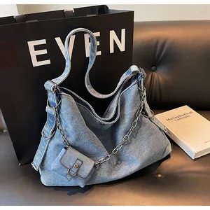 Detail of blue denim hobo bag with silver chain strap and mini coin purse attachment