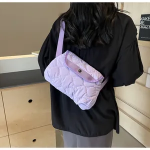 Light purple quilted crossbody bag with wave pattern and adjustable strap on model