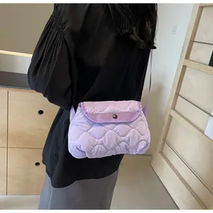 Detail view of purple quilted shoulder bag showing diamond pattern and metal snap button