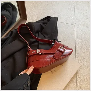 Macro shot of glossy burgundy leather bag with silver buckle on a black suit