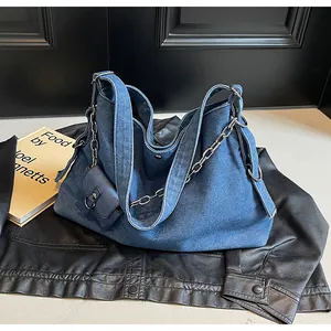 Detailed macro view of washed blue denim tote bag with silver chain and mini purse charm