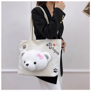 Detail of white canvas tote bag featuring a 3D plush bear and Ryhopm print on model