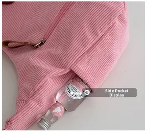 Detail of pink corduroy dumpling bag featuring functional side pocket and zip closure