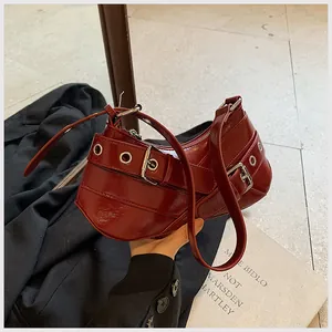 Detail view of burgundy underarm bag with glossy finish and silver metal eyelet straps