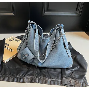 Detail shot of heavy washed denim hobo bag with thick metal chain and mini pouch accessory