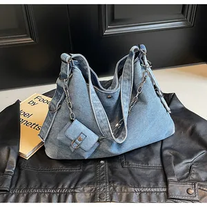 Detail of blue denim hobo bag featuring silver chain strap and mini pouch attachment