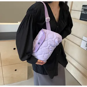 Close-up of light purple quilted crossbody bag with rhomboid patterns and button closure