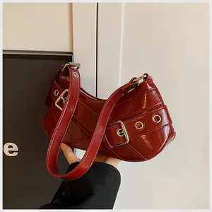 Detail of dark red glossy leather underarm bag with silver buckles and pleated texture
