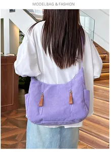 Detail of purple corduroy dumpling bag featuring side pockets and vertical zipper pockets