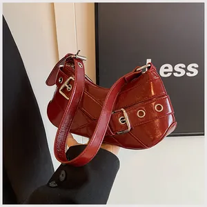 Detailed macro view of burgundy patent leather finish and silver buckles on shoulder bag