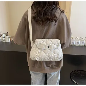 Detail of white quilted crossbody bag with rhombic pattern and canvas shoulder strap
