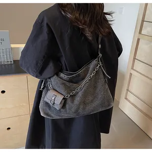 Detail view of large gray denim hobo bag with chain strap and small hanging pouch