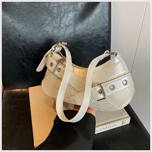 Detailed close-up of cream crescent underarm bag with silver buckles and metal eyelets