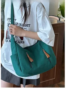 Detail of dark green corduroy shoulder bag showing vertical texture and zipper pockets