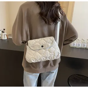 Detail of off-white quilted crossbody bag showing wavy stitching and round button