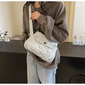 Detail view of light grey quilted crossbody bag with diamond stitching and flap button