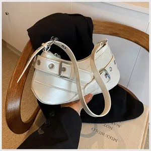 Detail of white leather underarm bag with silver grommets and textured strap detail