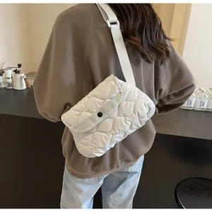 Detail of a quilted cloud crossbody bag in beige fabric with adjustable grey strap