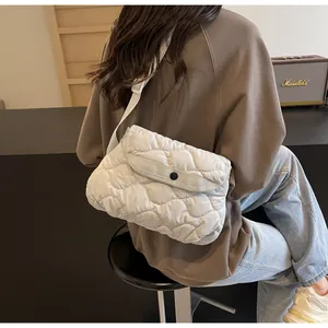 Detailed view of white quilted padded crossbody bag with adjustable fabric shoulder strap