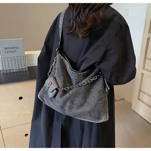 Detail of grey denim tote bag with silver chain, small pouch and washed texture finish