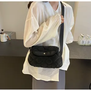 Detail of a black quilted cloud crossbody bag featuring a soft texture and metal buckle