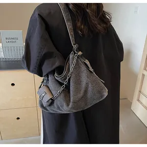 Detail of dark gray washed denim hobo bag with metal chain strap and matching mini pouch
