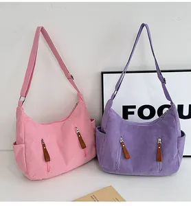 Detail view of pink and purple corduroy dumpling bags with dual zipper front pockets