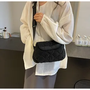 Detail of black quilted crossbody bag with adjustable wide strap and cloud texture
