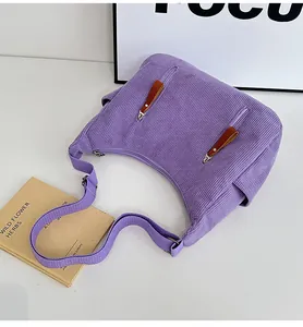 Detail view of purple corduroy dumpling bag with dual front zippers and leather pulls