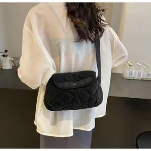 Rear view of black quilted puffer crossbody bag with adjustable wide strap on model