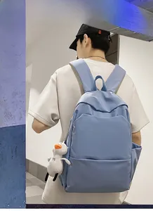 Detail of light blue waterproof backpack featuring a front zipper pocket and plush duck toy