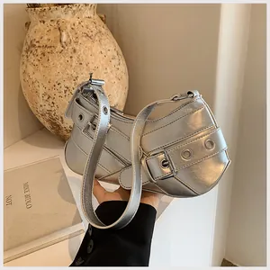 Detail of silver metallic underarm bag with decorative belt buckles and metal eyelets