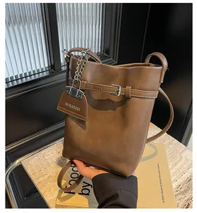 Detail of coffee brown PU leather bucket bag with metal chain and decorative buckle