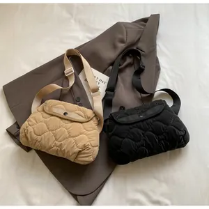 Close-up of quilted crossbody bags in khaki and black with wavy patterns and wide straps