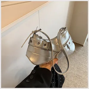 Detail of silver metallic underarm bag with punk eyelet straps and shiny mirror finish
