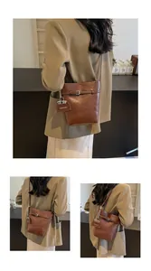 Detailed close-up of dark brown leather bucket bag featuring MIKAXIOI logo pendant