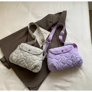 Detail of light grey and lavender quilted crossbody bags with wavy stitching and buckle