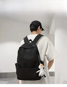 Rear view of a minimalist black waterproof backpack with a cute white duck pendant accessory
