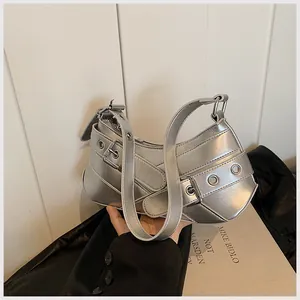 Close-up of silver metallic dumpling bag with Y2K style metal eyelets and belt details