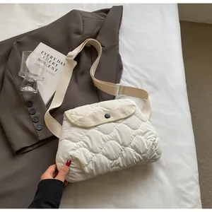 Detail of a quilted beige crossbody bag featuring wave patterns and an adjustable strap