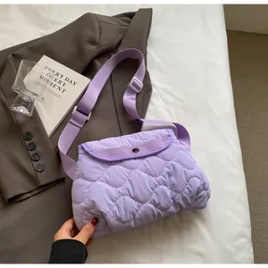 Close-up of purple quilted cloud bag with snap button and adjustable strap on blazer