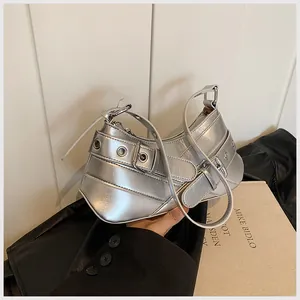 Silver metallic dumpling shoulder bag with punk buckles and eyelets held by a model