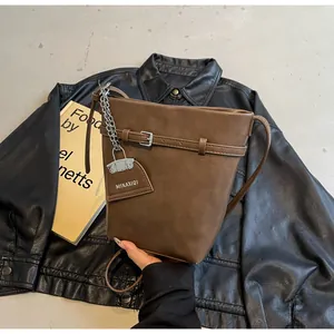 Detailed shot of dark brown bucket bag with silver buckle and MIKAXIQI logo pendant